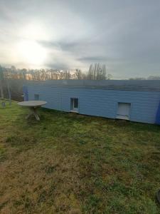 un edificio azul con una mesa de picnic en un campo en Le gîte du Vivier - Loches en Loches