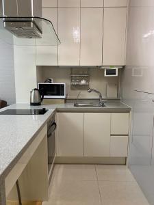 a kitchen with white cabinets and a sink at Хайвилл Астана G блок in Promyshlennyy