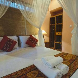 a bedroom with a white bed with towels on it at Aura Bisma Guesthouse in Ubud