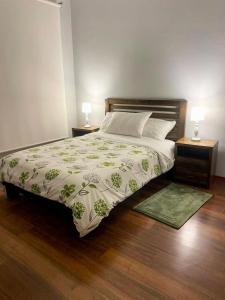 1 cama en un dormitorio con 2 mesitas de noche y 2 lámparas en Altos de Tababela, en Tababela