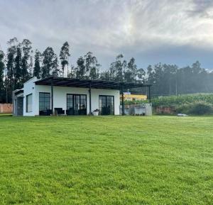 une maison blanche dans un champ avec un champ vert dans l'établissement Altos de Tababela, à Tababela