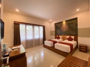 a bedroom with two beds and a desk at Putri Ayu Cottages in Ubud