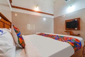 a bedroom with a bed and a tv on the wall at FabHotel Skyry I in Coimbatore
