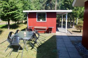 een tafel en stoelen voor een rode schuur bij Charming Cottage Close To The Beach in Vester Sømarken