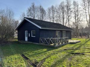 uma pequena casa preta com um alpendre de madeira num campo em Relaxing Vacation In Scenic Surroundings em Højby