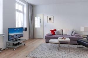 ein Wohnzimmer mit einem lila Sofa und einem TV in der Unterkunft Villa Eden Typ 4 Dependance in Binz