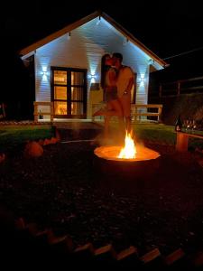 Una coppia che balla intorno al fuoco di fronte a una casa di Tiny House Canjerana- Morro do Eurico - Praia Grande-SC a Praia Grande