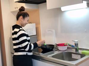 東京的住宿－bonart瀬田202，站在厨房准备食物的妇女
