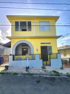 a yellow house with a fence in front of it at 310 Del Valle Central, Freshly Remodeled 3 Bedroom Home Sleeps 8 in San Juan
