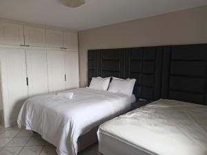 um quarto com 2 camas e lençóis brancos em Early Riser em Ezulwini