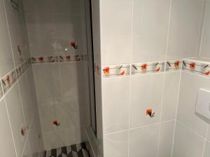 prysznic z białymi ścianami wyłożonymi kafelkami i pomarańczowymi kubkami w obiekcie Penzion Sokolov w mieście Sokolov