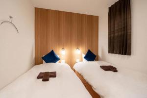 two beds with blue pillows in a room at ZONE SHINSAIBASHI WEST in Osaka