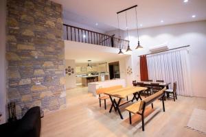 a living room with tables and chairs and a stone wall at Villa Queen Palm in Kumluca