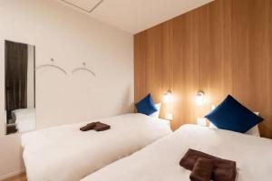 大阪的住宿－ZONE SHINSAIBASHI WEST，配有蓝色枕头的客房内的2张白色床