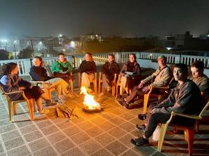 un grupo de personas sentadas alrededor de un fuego en GARG COMPLEX GUESTHOUSE, en Bharatpur