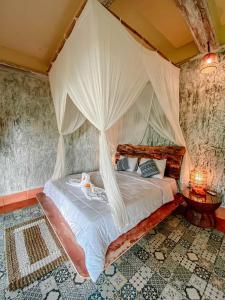 a bedroom with a canopy bed with curtains at Bali Inang Jungle View in Tampaksiring