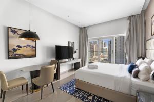 a hotel room with a bed and a table and a tv at Lovely Studio in Business Bay in Dubai
