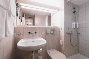 a white bathroom with a sink and a toilet at Hotel Thurgauerhof Self-Check-in in Weinfelden