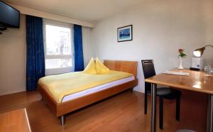 1 dormitorio con cama, escritorio y mesa en Hotel Thurgauerhof Self-Check-in, en Weinfelden