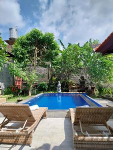 - une piscine avec 2 chaises en rotin dans l'établissement Puri Prana Guest House, à Ubud