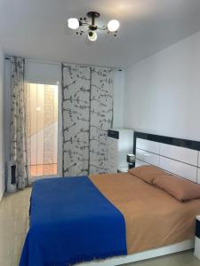 a bedroom with a large bed with a blue blanket at Apartamento en Playa Flamenca (residencial El Bosque) in Playas de Orihuela