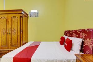 1 dormitorio con 1 cama con almohadas rojas y blancas en OYO 92792 Umi Rahayu Guesthouse, en Semarang