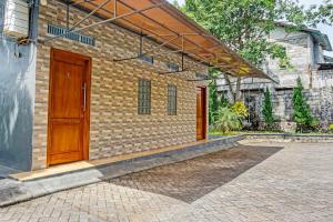 a brick building with two wooden doors on it at OYO 91679 Juanda Homestay Syariah in Pasuruan