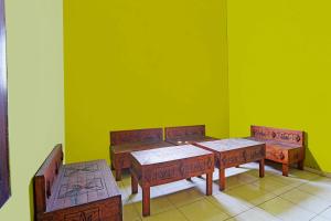 uma sala verde com duas mesas e dois bancos em OYO 91583 D’cost Green Syariah em Tambak-kidul