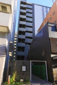 stayme THE HOTEL Ueno في طوكيو: مبنى اسود مع بوابة امام مبنى طويل
