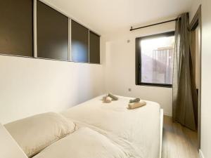 um quarto branco com uma cama e uma janela em Le caroubier em Beausoleil