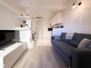 uma sala de estar com um sofá azul e uma cozinha em Le caroubier em Beausoleil