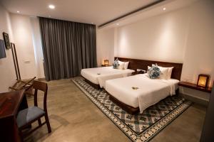 a hotel room with two beds and a desk at DACO Hotel in Siem Reap