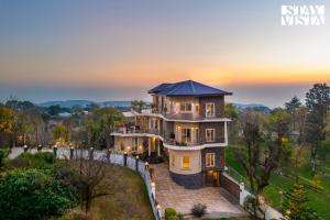 an aerial view of a house with a sunset at StayVista at Address By The Khul in Dharamshala