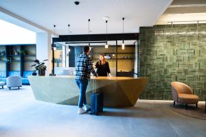 a man and a woman standing at a counter in an office at Porta Cité in Maasmechelen