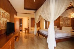 um quarto com uma cama de dossel e uma televisão em Champlung Sari Villa & Spa Ubud em Ubud