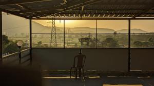 une chaise assise dans une pièce avec vue sur un champ dans l'établissement Blue Bell Homestay, à Lonavala