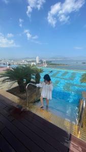 a girl in a white dress standing in a swimming pool at Luxury Ocean View Danang Golden Bay in Da Nang