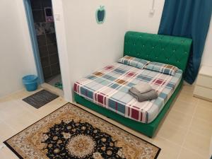 a bedroom with a bed with a green headboard at D'RinduVillage Homestay in Marang