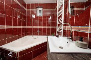 a red tiled bathroom with a sink and a tub at Casa Ryu in Cluj-Napoca