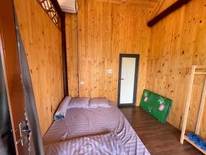 um quarto com uma cama num chalé de madeira em THE LAND OF LOVE Homestay - Venuestay em Dak Lak