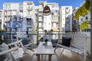 a balcony with white chairs and a table and some buildings at House Putignani 181 in Bari