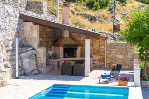 a house with a swimming pool and a fireplace at Villa Stone House Kuna in Pridvorje