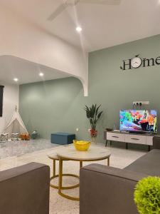a living room with a table and a tv at IPOH LYL EVERGREEN HOMESTAY 12pax in Ipoh