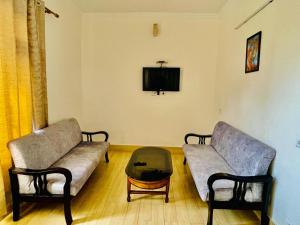 a living room with two couches and a coffee table at Hotel Suryadev in Pālampur