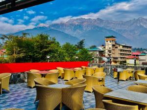 a row of tables and chairs on a balcony with mountains at Hotel Suryadev in Pālampur
