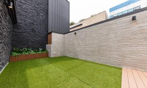 a backyard with a brick wall and green grass at Cheongju Hotel Dictionary in Cheongju