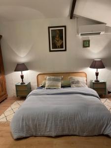 a bedroom with a large bed with two lamps at charme de l'ancien au coeur de la vallée sud charentaise in Bardenac