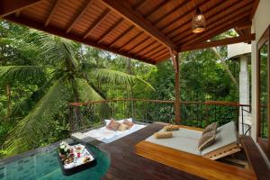 a patio with a bed and a table on a deck at Jannata Resort and Spa in Ubud