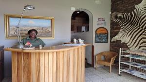 a man is standing at a counter in a store with a counter at Bird's Nest Guest House in Keetmanshoop