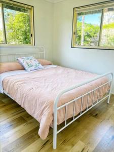 a bed in a bedroom with two windows at Cosy house among the trees in Pemberton